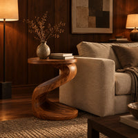 Twisting s shape side table with a circular top and wide disc base in an evening living room with walnut wall paneling