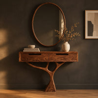Console table with a two drawer box on a single branching tree pedestal in a dark studio against a charcoal plaster wall
