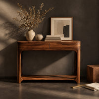 Corner detail of console table with a two panel front rail and a low open shelf beside wood, brass and linen samples