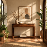 Console table with a two panel front rail and a low open shelf in a bright entryway with arched windows and plants
