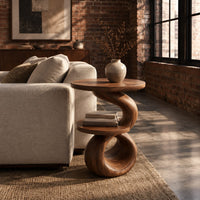 Two tier end table with a spiral ribbon base and a loop foot in an industrial loft living room with exposed brick