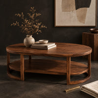 Corner detail of two tier oval wooden coffee table with slim legs and half ring supports beside wood, brass and linen samples