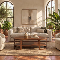 Two tier oval wooden coffee table with slim legs and half ring supports in a bright living room with arched windows and plants
