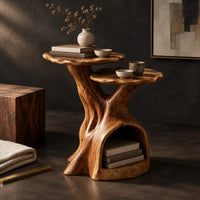 Corner detail of two tier side table with a trunk base and a hollow for books beside wood, brass and linen samples