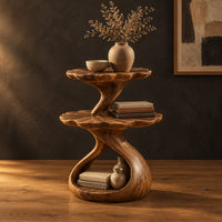 Two tier side table with scalloped tops and a twisting stem in a dark studio against a charcoal plaster wall