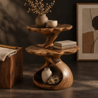 Corner detail of two tier side table with scalloped tops and a twisting stem beside wood, brass and linen samples