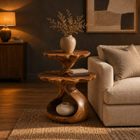 Two tier side table with scalloped tops and a twisting stem in a dark living room at golden hour