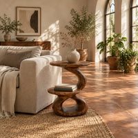 Two tier side table with a twisted stem and a figure eight base in a bright living room with arched windows and plants