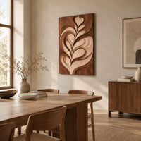 Wall art panel with a carved leaf relief in light and dark tones beside a dining table in natural light
