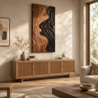 Tall wall art panel split between natural wood grain and black carved ripples above a light oak sideboard in daylight