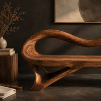 Corner detail of wooden bench with a wavy looped rim and slender splayed legs beside wood, brass and linen samples