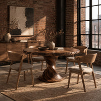 Round dining table on a twisted pedestal with a flared disc base in an industrial loft dining room with exposed brick