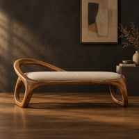 Bench with a padded seat and an arched back rail on open loop legs in a dark studio against a charcoal plaster wall