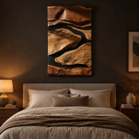 Vertical carved wall art with flowing forms on a dark ground above a bed in a dusk lit bedroom