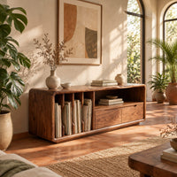 Low tv stand with vertical slots, an open shelf and two drawers in a bright living room with arched windows and plants