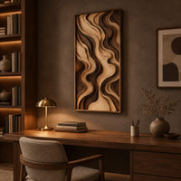 Tall framed wall art with layered wave relief in light and dark wood above a desk in a dark study corner
