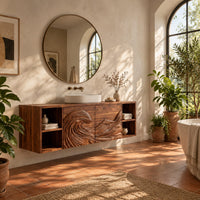 Wall mounted bathroom vanity with carved wave panels and open end shelves in a bright bathroom with arched windows and plants