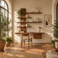 Wall mounted wooden desk with staggered shelves above a wide work top in a bright home office with arched windows and plants