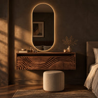 Floating makeup vanity with an open top niche and a wave carved front in a dark bedroom at golden hour