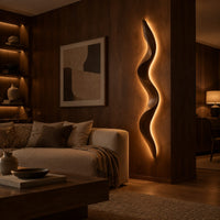 Tall wavy wall sconce that glows softly along its back edge in an evening living room with walnut wall paneling