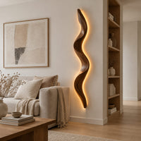 Tall wavy wall sconce that glows softly along its back edge in a Scandinavian living room with white walls