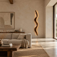 Tall wavy wall sconce that glows softly along its back edge in a bright open plan living room