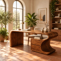 Sculpted wood desk with a waterfall side panel and a two drawer pedestal in a bright home office with arched windows and plants