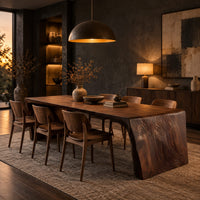 Waterfall dining table with carved grain slab ends and open space below in a dark dining room at golden hour