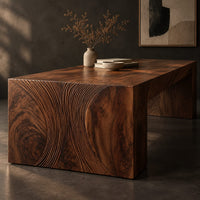 Corner detail of waterfall dining table with carved swirl grain end panels beside wood, brass and linen samples