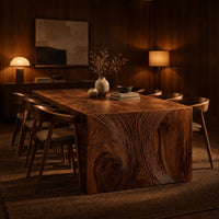 Waterfall dining table with carved swirl grain end panels in an evening dining room with walnut wall paneling