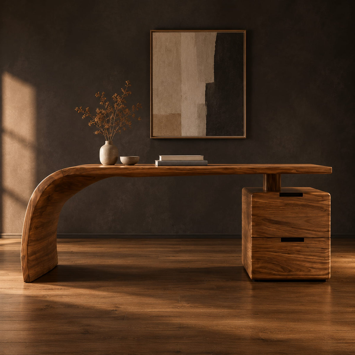 Desk with a sweeping waterfall leg and a two drawer pedestal in a dark studio against a charcoal plaster wall