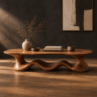 Coffee table with a freeform slab top on a rolling wave shaped base in a dark studio against a charcoal plaster wall