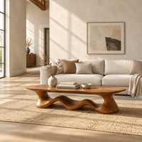 Coffee table with a freeform slab top on a rolling wave shaped base in a bright open plan living room
