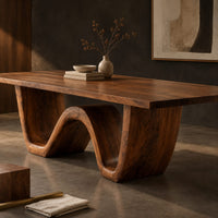 Corner detail of rectangular dining table on a thick wave shaped base beside wood, brass and linen samples