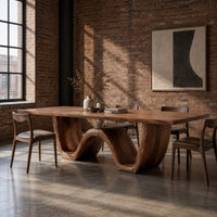 Rectangular dining table on a thick wave shaped base in an industrial loft dining room with exposed brick