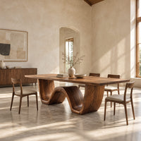 Rectangular dining table on a thick wave shaped base in a bright open plan dining room