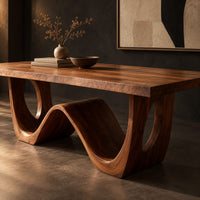 Corner detail of rectangular dining table with a wave shaped base and open arch ends beside wood, brass and linen samples