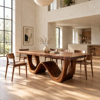 Rectangular dining table with a wave shaped base and open arch ends in a bright open plan dining room