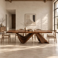 Rectangular dining table with a thick slab top on two ribbon like wave legs in a bright open plan dining room