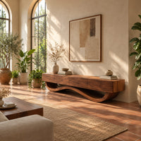Long tv stand with four flush front panels on a wave shaped base in a bright living room with arched windows and plants