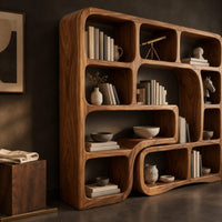 Corner detail of bookshelf with flowing wave dividers and open cubbies of mixed sizes beside wood, brass and linen samples