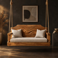 Wooden swing with a wave carved back and a long seat cushion in a dark studio against a charcoal plaster wall