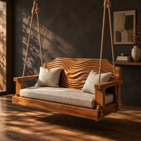 Wooden swing with a wave carved back and a long seat cushion, three-quarter view showing the grain