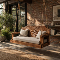 Wooden swing with a wave carved back and a long seat cushion in an industrial loft porch with exposed brick