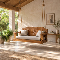 Wooden swing with a wave carved back and a long seat cushion in a bright open plan porch