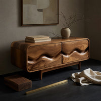 Corner detail of mid century TV cabinet with wave carved doors beside wood, brass and linen samples