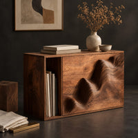 Corner detail of end table with a carved wave front and an open side compartment beside wood, brass and linen samples