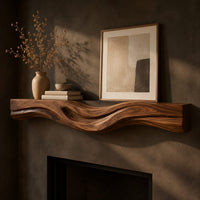 Corner detail of thick wood fireplace mantel with a wave carved front and flowing grain beside wood, brass and linen samples