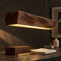 Corner detail of linear wooden pendant light with wave carved sides and a glowing underside beside wood, brass and linen samples