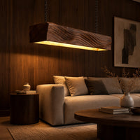 Linear wooden pendant light with wave carved sides and a glowing underside in an evening living room with walnut wall paneling